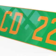 Plaque verte et orange avec les numéros "123 CD 22" en gros caractères. D'autres plaques similaires sont empilées en dessous.