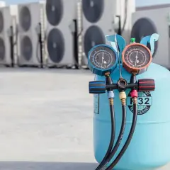 Bouteille de gaz R32 pour climatisation de voiture, avec manomètres, devant des unités extérieures de climatisation.