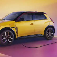 La Renault 5 électrique, jaune vif, se recharge. Une borne de recharge est connectée à la voiture, prête pour l'aventure.