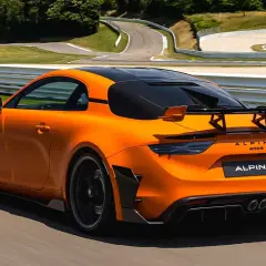 Alpine A110 R orange sur circuit, prête à atteindre sa vitesse max. L'aérodynamisme agressif et le spoiler arrière promettent des performances exceptionnelles.