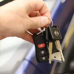 Une main tient les clés d'une voiture Nissan, symbolisant la signature d'un contrat de location voiture.