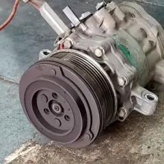Compresseur de climatisation automobile, prêt pour son remplacement. Pièce mécanique essentielle pour le confort de conduite.