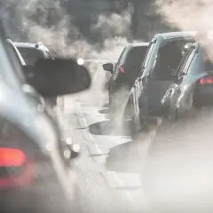 Fumée épaisse sortant de la clim de voitures dans un embouteillage. L'air est saturé de vapeur, rendant la visibilité difficile.