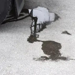 Une flaque sombre sur le bitume, près d'un pneu, suggère une fuite liquide de frein.