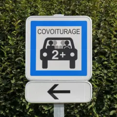 Panneau de signalisation "Covoiturage" indiquant une voie réservée aux véhicules de 2 personnes ou plus. Une flèche noire pointe vers la gauche.