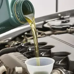 Huile neuve versée dans un entonnoir pour faire vidange voiture. Le moteur est visible en arrière-plan.