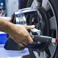Mains ajustant un appareil sur une roue pour l'équilibrage pneu et parallélisme.