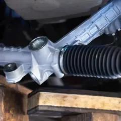 Système de direction assistée d'une voiture, avec une crémaillère de direction visible. Un symptôme de problème pourrait être un bruit inhabituel.