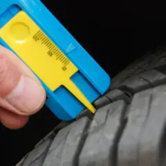 Mesure de la bande de roulement d'un pneu avec un jauge. Le résultat indique une usure trop importante, synonyme de refus contrôle technique pneu.