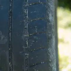 Gros plan sur la bande de roulement d'un pneu usé, montrant les rainures et les blocs de caoutchouc.