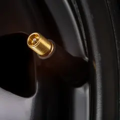 Gros plan sur une valve de pneu dorée, prête à changer.