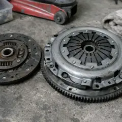 Deux pièces d'embrayage usées sur un sol en béton. L'embrayage peut-il casser d'un coup ? Ces pièces montrent les signes d'une usure importante.