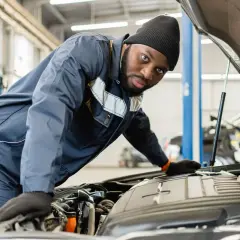 Mécanicien concentré sur le moteur d'une voiture. Il vérifie le niveau d'huile, une étape clé pour savoir combien de temps dure une vidange.