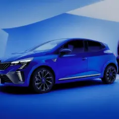 Une petite voiture confortable pour faire de la route, d'un bleu éclatant, se tient dans un décor épuré. Une silhouette féminine se détache en arrière-plan.