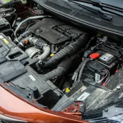 Vue détaillée du compartiment moteur d'une voiture diesel, prêt pour un entretien. On y voit le bloc moteur, la batterie et divers composants.