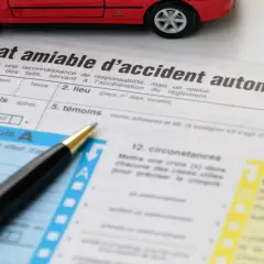 Un stylo et une voiture rouge sur un constat amiable à télécharger. Ce document sert à déclarer un accident automobile.
