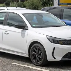 Une Opel Corsa blanche, prête à démarrer avec son moteur efficace, se gare à côté d'autres véhicules.