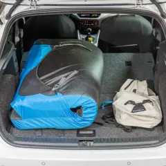 Le coffre d'une Seat Arona est chargé d'un grand sac de couchage bleu et noir et d'un sac à dos beige, prêt pour une aventure.