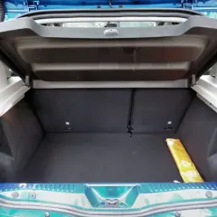 Le coffre d'une Dacia Sandero, vide et propre, prêt à accueillir vos bagages. Un triangle de signalisation jaune est visible sur le côté.