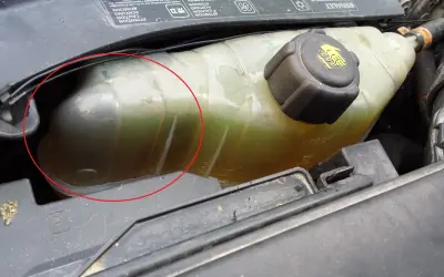 Réservoir de liquide de refroidissement d'une Clio 3, le niveau est bas. Le liquide est verdâtre et trouble.