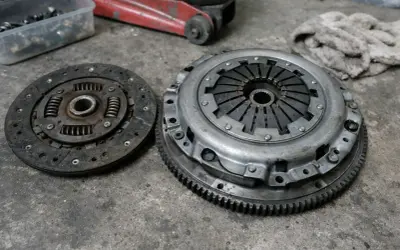 Deux pièces d'embrayage usées sur un sol en béton. L'embrayage peut-il casser d'un coup ? Ces pièces montrent les signes d'une usure importante.