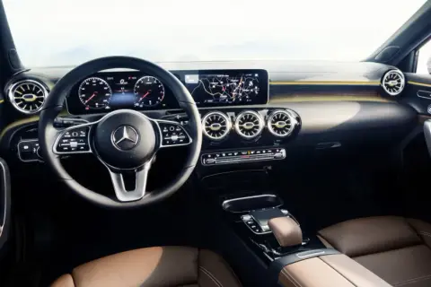 L'intérieur luxueux de la Mercedes Classe A, avec ses sièges en cuir brun, son volant moderne et son grand écran d'infodivertissement.