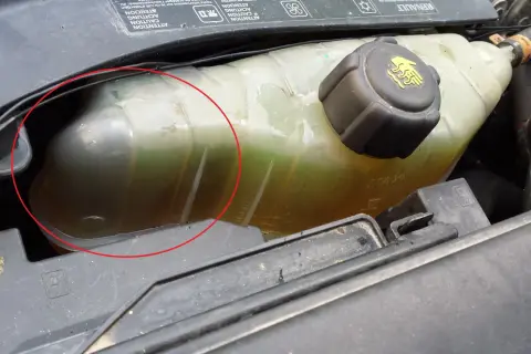 Réservoir de liquide de refroidissement d'une Clio 3, le niveau est bas. Le liquide est verdâtre et trouble.