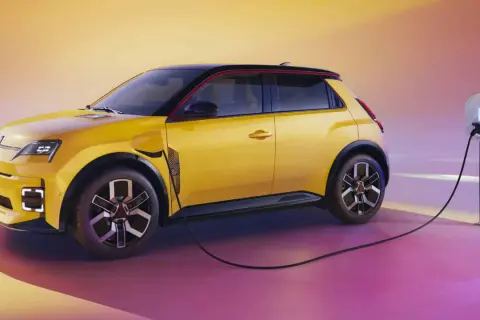 La Renault 5 électrique, jaune vif, se recharge. Une borne de recharge est connectée à la voiture, prête pour l'aventure.