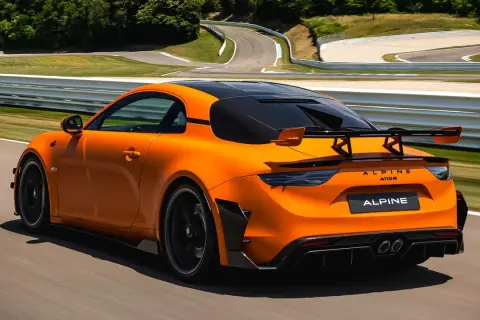 Alpine A110 R orange sur circuit, prête à atteindre sa vitesse max. L'aérodynamisme agressif et le spoiler arrière promettent des performances exceptionnelles.