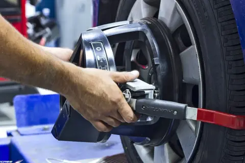 Mains ajustant un appareil sur une roue pour l'équilibrage pneu et parallélisme.