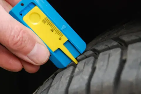 Mesure de la bande de roulement d'un pneu avec un jauge. Le résultat indique une usure trop importante, synonyme de refus contrôle technique pneu.