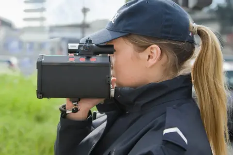 Agent de police utilisant un radar pour mesurer la vitesse. Même un excès de vitesse inférieur à 5 km/h peut être verbalisé.