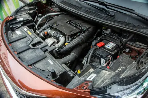 Vue détaillée du compartiment moteur d'une voiture diesel, prêt pour un entretien. On y voit le bloc moteur, la batterie et divers composants.