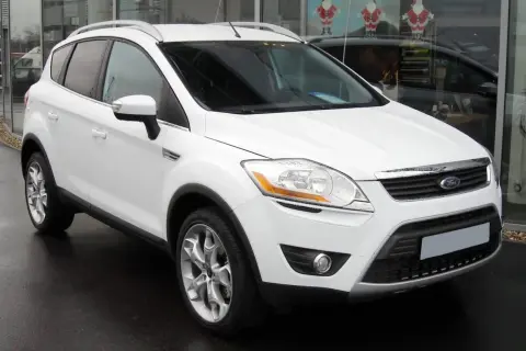 Un Ford Kuga blanc, symbole de fiabilité, garé devant un showroom.