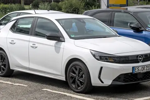 Une Opel Corsa blanche, prête à démarrer avec son moteur efficace, se gare à côté d'autres véhicules.