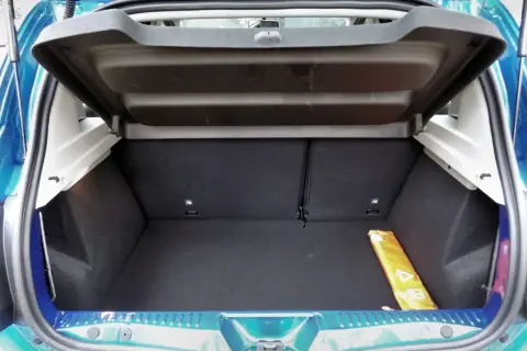 Le coffre d'une Dacia Sandero, vide et propre, prêt à accueillir vos bagages. Un triangle de signalisation jaune est visible sur le côté.