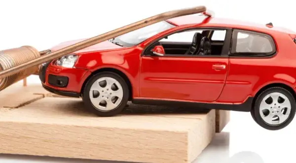 Une petite voiture rouge est piégée sur une souricière. Attention, voici comment acheter une voiture d'occasion sans tomber dans le piège !