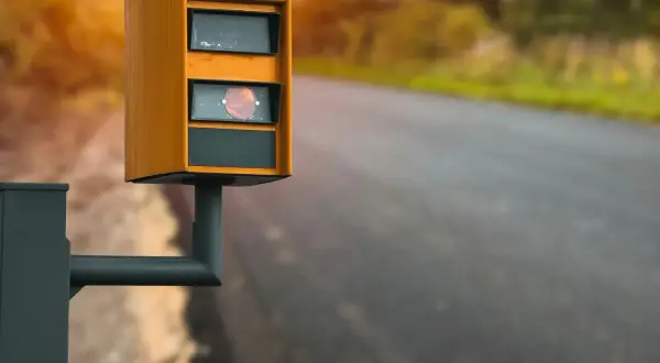 Radar de vitesse orange sur le bord de la route, rappelant de ne pas utiliser le téléphone au volant.