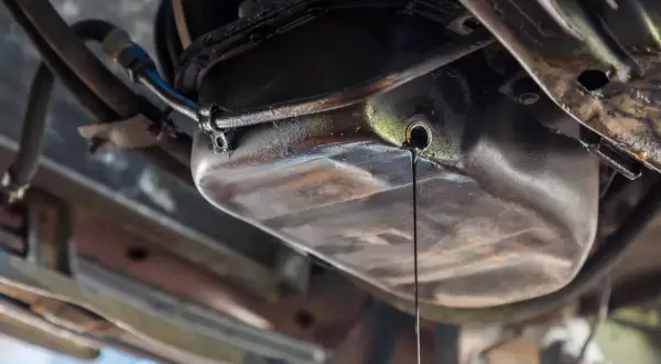 Goutte d'huile moteur s'écoulant du carter. Une fuite à réparer, le prix peut varier.