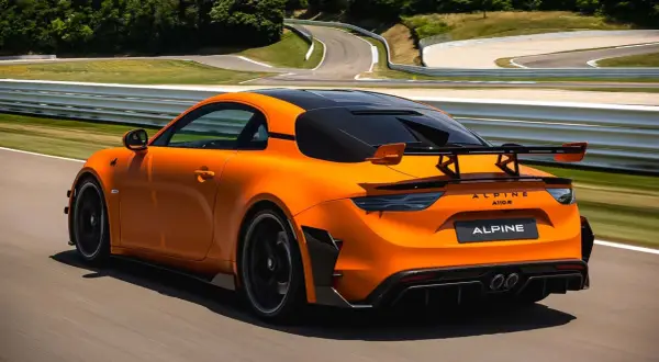 Alpine A110 R orange sur circuit, prête à atteindre sa vitesse max. L'aérodynamisme agressif et le spoiler arrière promettent des performances exceptionnelles.