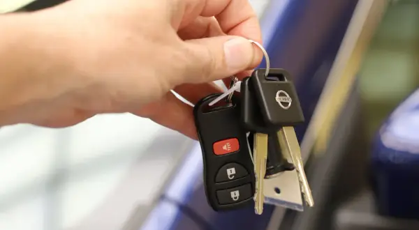 Une main tient les clés d'une voiture Nissan, symbolisant la signature d'un contrat de location voiture.