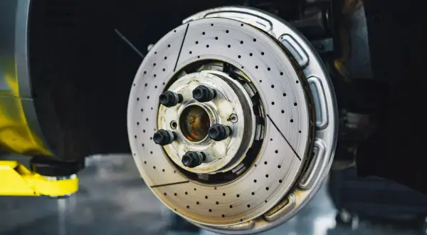Disque de frein perforé et ventilé, prêt à arrêter la voiture. Ce frein qui siffle pourrait indiquer un besoin de maintenance.