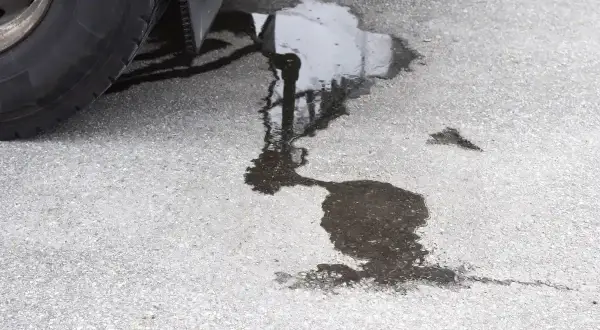 Une flaque sombre sur le bitume, près d'un pneu, suggère une fuite liquide de frein.