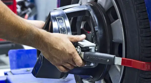 Mains ajustant un appareil sur une roue pour l'équilibrage pneu et parallélisme.