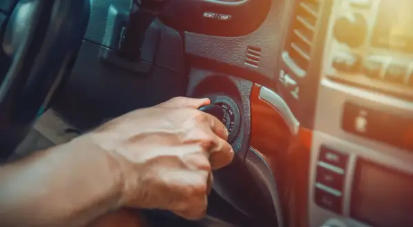 Main d'un conducteur tournant la clé de contact, espérant que la voiture cale en roulant ne se reproduise pas.