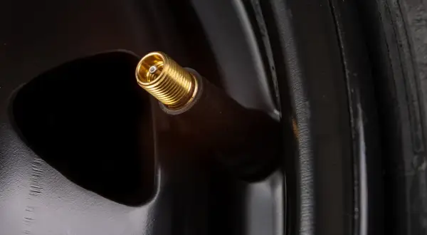 Gros plan sur une valve de pneu dorée, prête à changer.