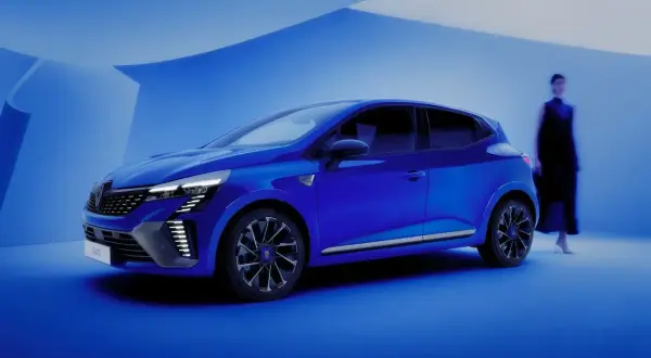 Une petite voiture confortable pour faire de la route, d'un bleu éclatant, se tient dans un décor épuré. Une silhouette féminine se détache en arrière-plan.
