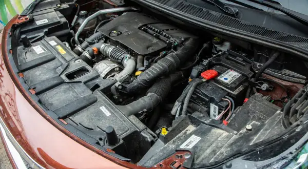 Vue détaillée du compartiment moteur d'une voiture diesel, prêt pour un entretien. On y voit le bloc moteur, la batterie et divers composants.