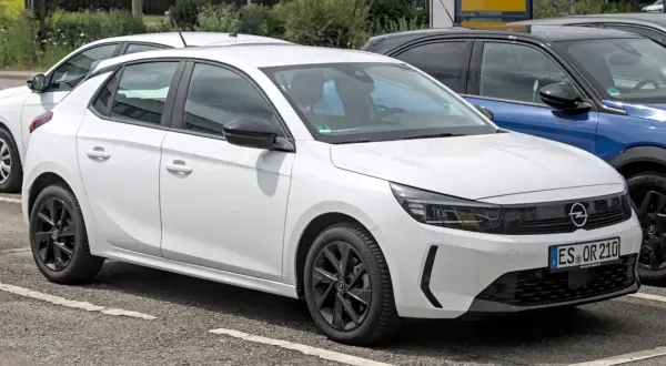 Une Opel Corsa blanche, prête à démarrer avec son moteur efficace, se gare à côté d'autres véhicules.