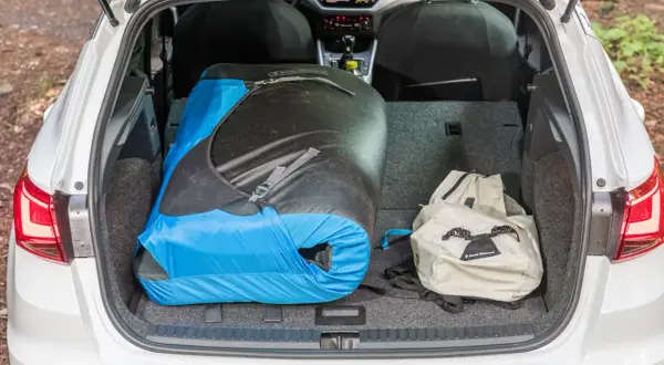 Le coffre d'une Seat Arona est chargé d'un grand sac de couchage bleu et noir et d'un sac à dos beige, prêt pour une aventure.